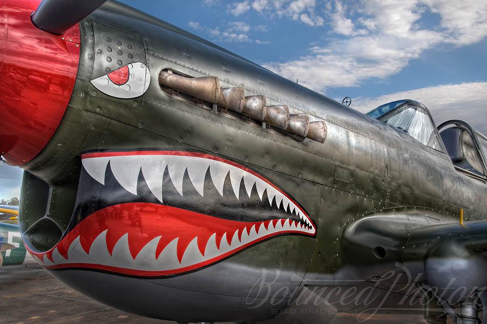 Curtiss P-40 Kittyhawk on display with a smile after a day of aerobatics at Temora Aviation Museum. P-40 is all-metal fighter and ground attack aircraft designed in US and used in 28 nations during the World War II. It was the main fighter aircraft used by the Royal Australian and New Zealand Air Forces. This particular one was assembled in 1st Aircraft Depot at Hobsonville, New Zealand in June 1943 and assigned to 2nd Operational Training Unit. After the war it did escape the fate of being scrapped and was eventually bought by Allan Arthur. It took 8 years to fully restore the aircraft and I was lucky enough to see its amazing display that day at Temora. Only 19 of them remain airworthy out of 13,738 built. This is a tone-mapped HDR from 3 RAW files shot handheld with my Nikon D90.